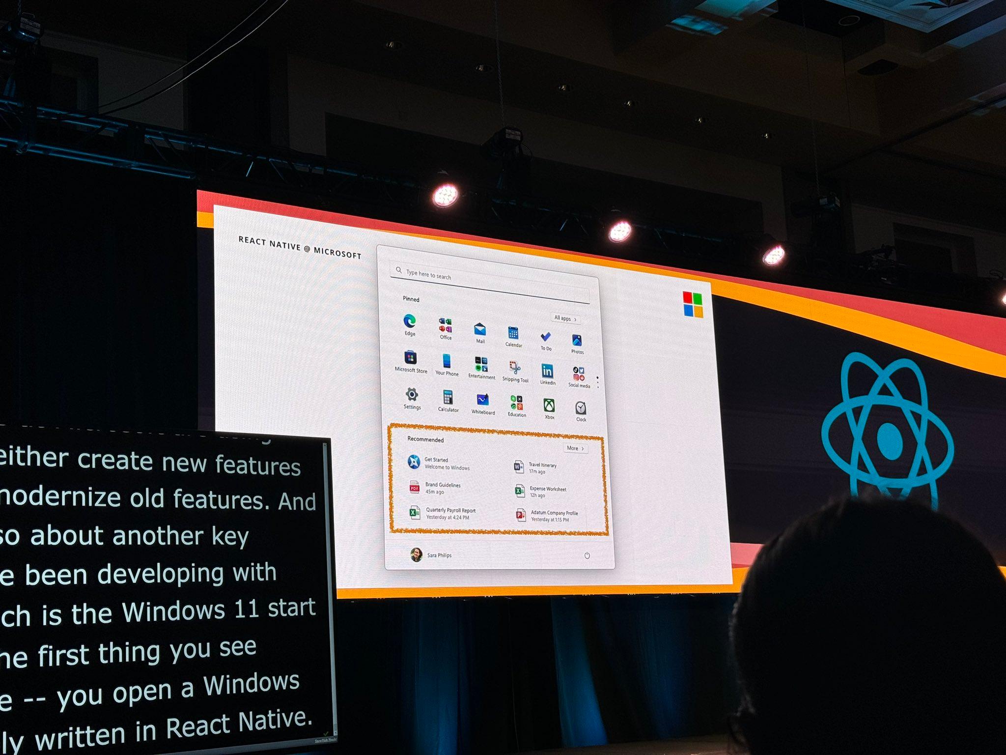 A presentation slide displayed at ReactConf shows a section of the Windows 11 Start menu, highlighting that parts of the system UI are built using React Native. The slide features the React Native logo and a screenshot of the Start menu with pinned apps and recommended items.